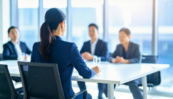 会議で発言をする女性社員の後ろ姿 会議で発言をする女性社員の後ろ姿の写真