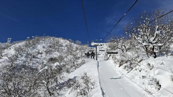 スキー場の高速リフトに乗るスノーボーダー リフト,クワッドリフト,搬器の写真素材