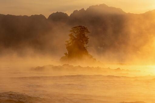 朝日に浮かび上がる女岩の神秘 毛嵐,日の出,朝日の写真素材