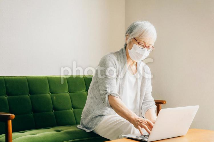 ノートパソコンを使う高齢者女性（マスク姿） ノートパソコン,ビデオ通話,高齢者の写真素材