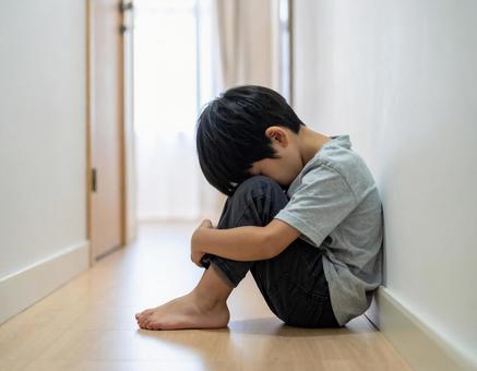 廊下で一人うつむく男の子の写真