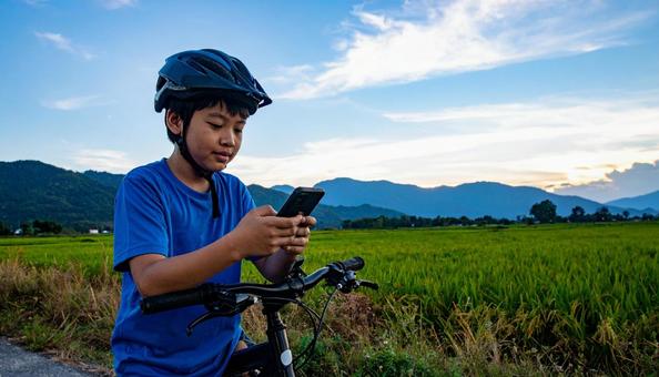 自転車を止めてスマホを見る男の子 自転車を止めてスマホを見る男の子の写真