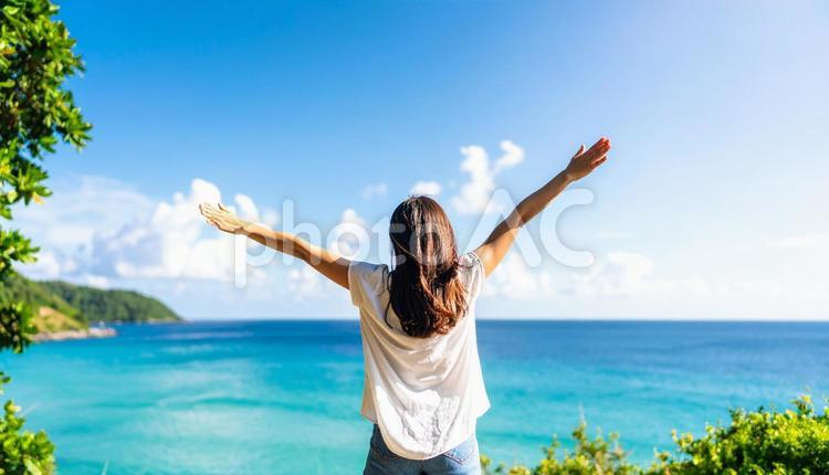 青空に向かって両手を広げる女性の後ろ姿 ビーチ,夏,海の写真素材