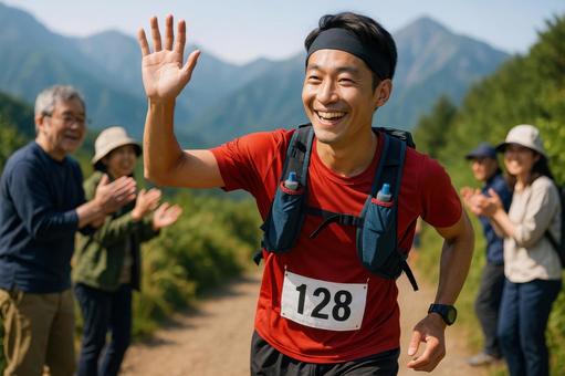 沿道の応援に手を振るトレイルランナー 沿道の応援に手を振るトレイルランナーの写真