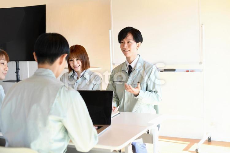 屋内で会議をする作業服を着た若い男女達 作業服,作業員,打ち合わせの写真素材