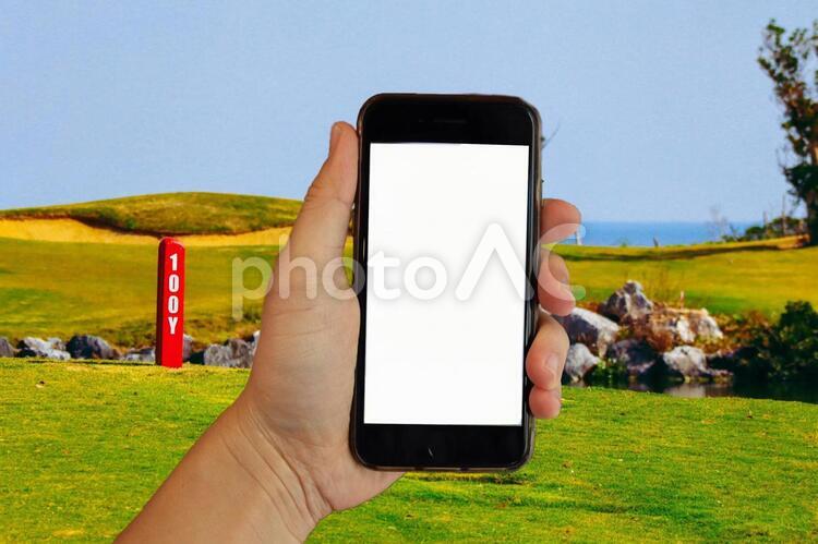写真素材: iPhoneを持つ手 画面白抜き ゴルフ場背景 iphone,手,モバイルの写真素材
