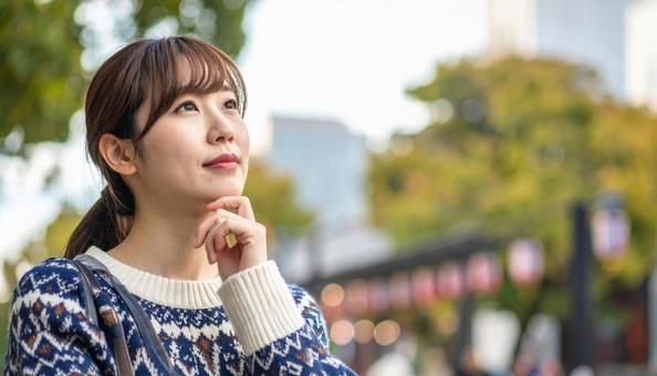 顎に手をやり考える女性の写真