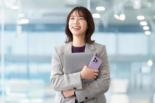 パソコンとスマホを持つ笑顔の女性 パソコンとスマホを持つ笑顔の女性 女性,パソコン,スマホの写真素材