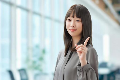 人差し指を立てて案内する笑顔の女性 女性,笑顔,指の写真素材
