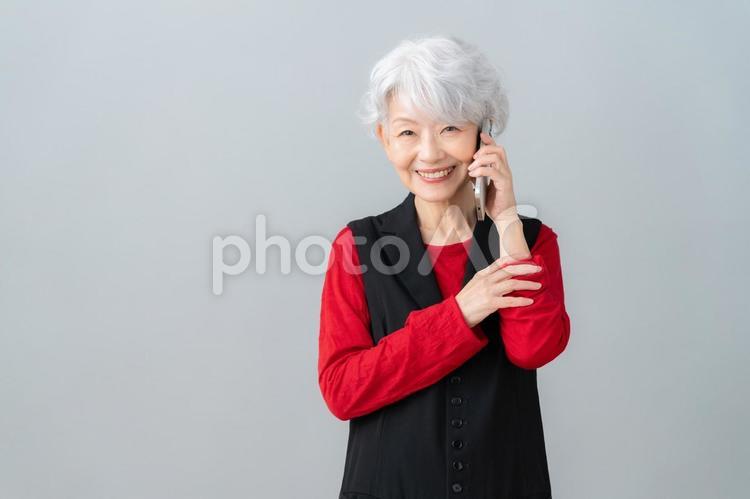 グレーバックでスマホを見るシニアの女性 シニア,女性,スマホの写真素材
