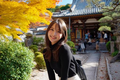 紅葉とお寺を背景にした笑顔の女性の写真