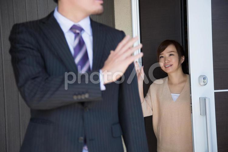玄関で夫を送り出す妻（妻にピント） 出勤,笑顔,夫婦の写真素材