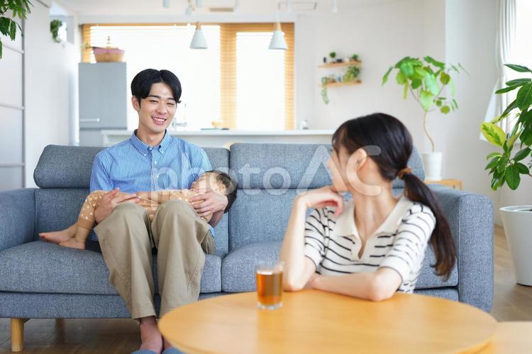 寝ている子供を抱く男性を見る女性 親子,寝る,抱っこの写真素材