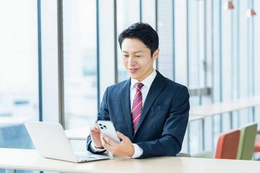 オフィスでスマホを見るビジネスマン ビジネスマン,スマートフォン,オフィスの写真素材