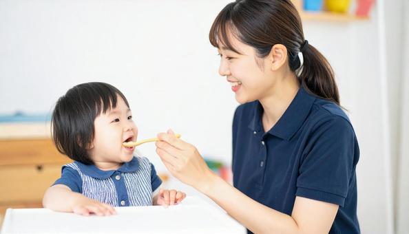 子どもにご飯をあげる保育士 子どもにご飯をあげる保育士の写真