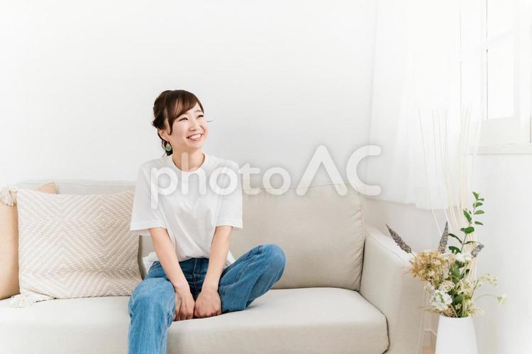 ソファに座る笑顔の日本人女性（紫外線） 女性,笑顔,窓の写真素材