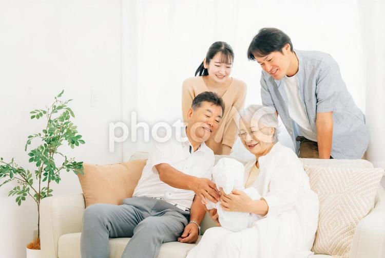 赤ちゃんを抱いた老夫婦と若い夫婦（里帰り） 孫,里帰り,帰省の写真素材