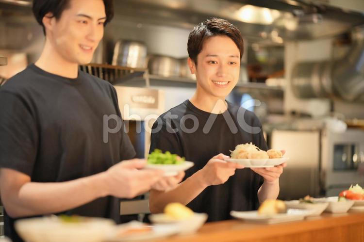 カウンターでおかずを出す男性たち 男性,大学生,バイトの写真素材