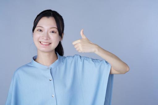 グッドポーズをした青い服の女性の写真