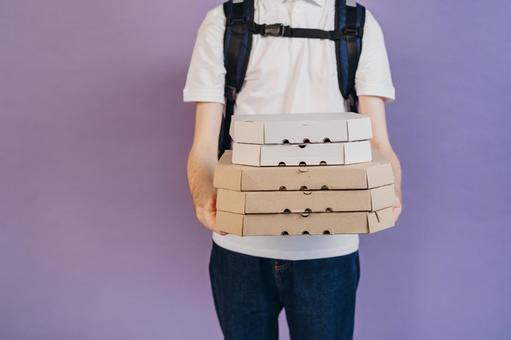 ピザの箱を重ねて抱えている男性（紫背景） 配達,デリバリー,配送の写真素材