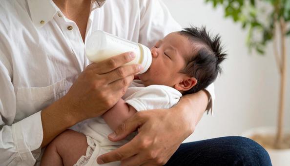 椅子に座り赤ちゃんに哺乳瓶で授乳する父親 椅子に座り赤ちゃんに哺乳瓶で授乳する父親の写真