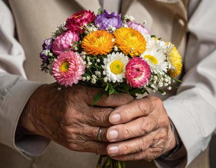お供えの花を持つ高齢の手 お供えの花を持つ高齢の手の写真