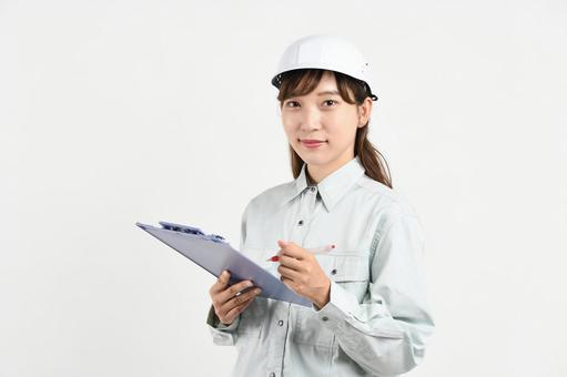 ボードを持つ作業服姿の若いアジア人女性 建設建設現場,現場作業,作業着の写真素材