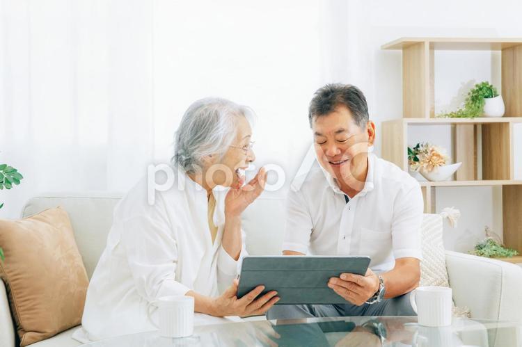 タブレットPCを見る高齢者夫婦(笑顔) タブレットPCを見る高齢者夫婦(笑顔) 高齢者,タブレット,光テレビの写真素材
