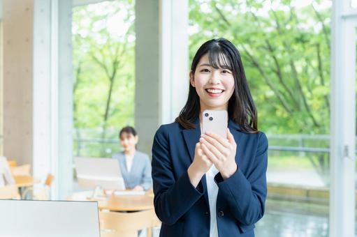 オフィスでスマホを使うビジネスウーマン オフィスでスマホを使うビジネスウーマン ビジネスウーマン,スマホ,笑顔の写真素材