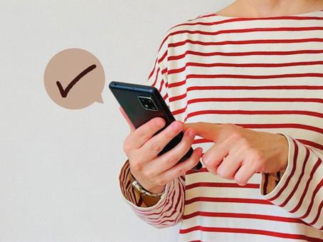 スマホからお店の予約をする女性 スマホからお店の予約をする女性 スマホ,女性,チェックの写真素材