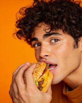 視線が印象的なハンバーガーを食べる男性 視線が印象的なハンバーガーを食べる男性の写真