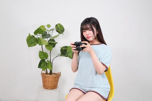 部屋着でコンパクトカメラを操作する女性 部屋着でコンパクトカメラを操作する女性 女性,若い,20代の写真素材