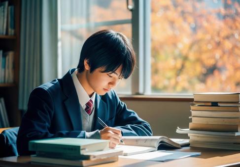 秋の教室で勉強に集中する男子学生 秋の教室で勉強に集中する男子学生の写真