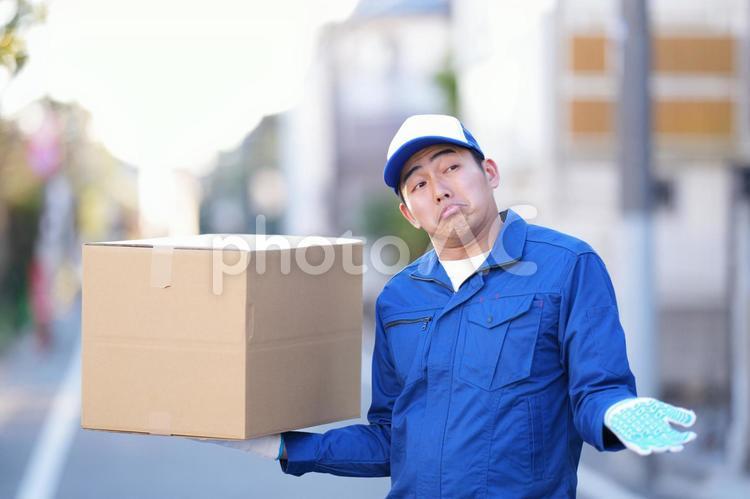 屋外で段ボール箱を手に乗せてお手上げポーズの引っ越し作業員 引っ越し,男性,日本人の写真素材