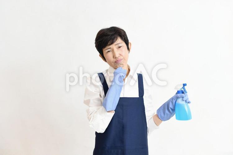 洗剤を持ち悩むエプロン姿の中高年女性 主婦,掃除,洗剤の写真素材