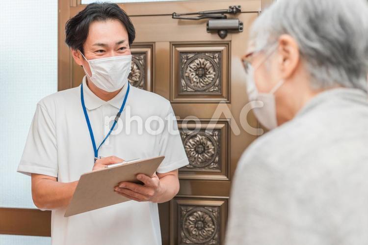高齢者住宅に訪問する男性（書類・マスク） 民生委員,安否確認,高齢者の写真素材