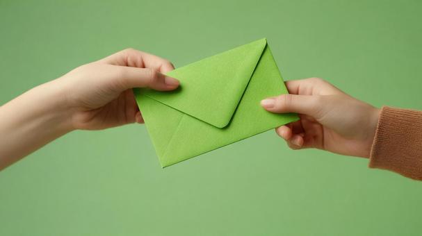 緑色の封筒を受け渡す手元 緑色の封筒を受け渡す手元の写真