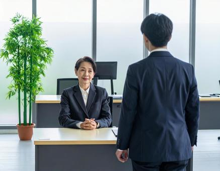 女性上司とその前に立つサラリーマンの部下の写真