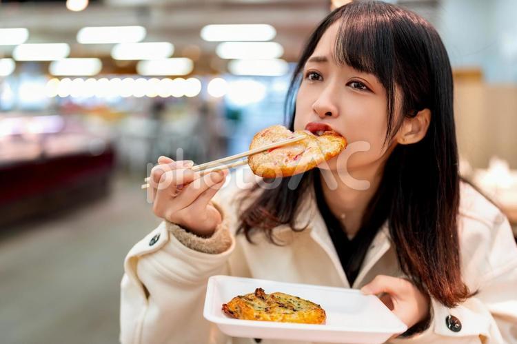 炉端焼きで買った練り物を食べる若い女性 女性,若い,炉端焼きの写真素材
