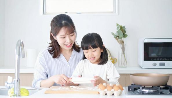 キッチンで楽しそうに料理をする母娘 キッチンで楽しそうに料理をする母娘の写真