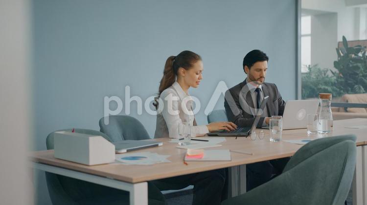 会議室のテーブルでノートパソコンを使ってプレゼンテーションの準備をする男女 コワーキング,ビジネス,女性の写真素材
