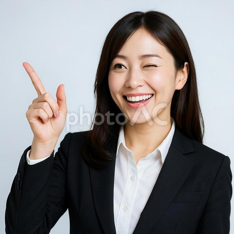 ウィンクしながら指差す女性 ビジネスウーマン,スーツ,笑顔の写真素材