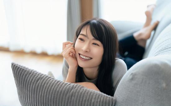 ソファに寝転ぶ笑顔の女性 ソファに寝転ぶ笑顔の女性の写真