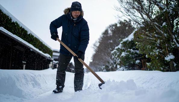 大雪が降った日の翌日の朝に雪かきする男性 大雪が降った日の翌日の朝に雪かきする男性の写真