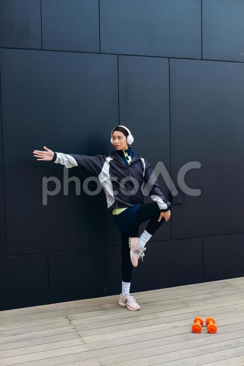 足を上げて手を伸ばす女性 女性,ヘッドフォン,人物の写真素材