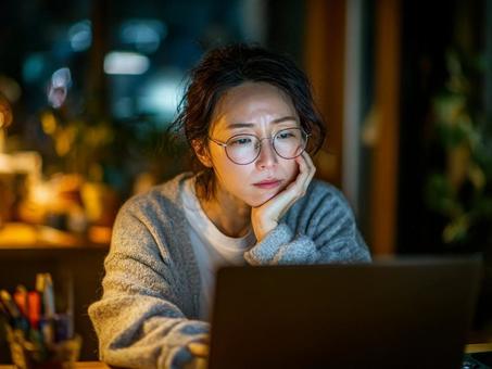 夜遅くにパソコンで調べものをする女性の写真