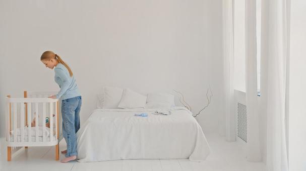 ベビーベッドの赤ちゃんを見る横向き女性 ベビーベッドの赤ちゃんを見る横向き女性 女性,横向き,横顔の写真素材