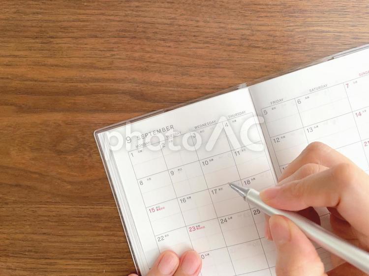9月のスケジュール帳に記入する女性の手元 スケジュール帳,書く,手の写真素材
