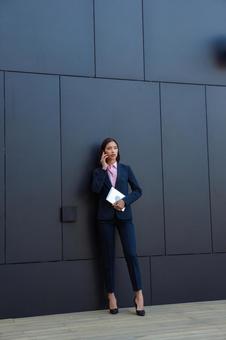オフィスビルの黒い壁の前で電話するアジア人女性 ビジネスウーマン,ビジネス,女性の写真素材