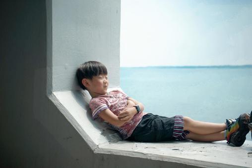＜素材＞夏の海辺のトンネルで休む男の子 子供,笑顔,海の写真素材